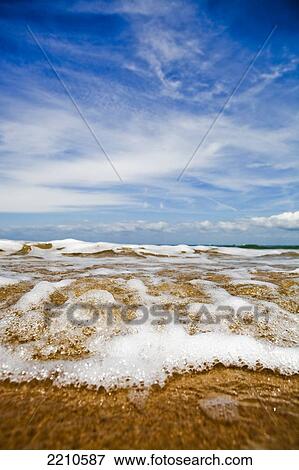 Stock Photo - Sea washing in onto sandy beach. Fotosearch