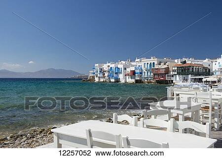Stock Image - Seafront taverna tables in the Little Venice area; Mykonos Town, Mykonos, Cyclades, Greek Islands, Greece. Fotosearch