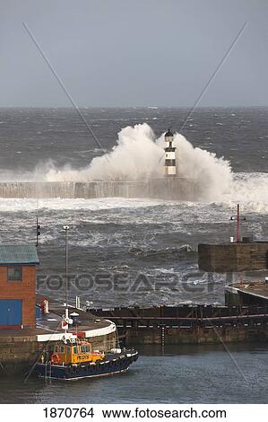 Picture - Seaham, Teesside, England; Waves Crashing Into A Lighthouse And A Boat Along The Pier. Fotosearch