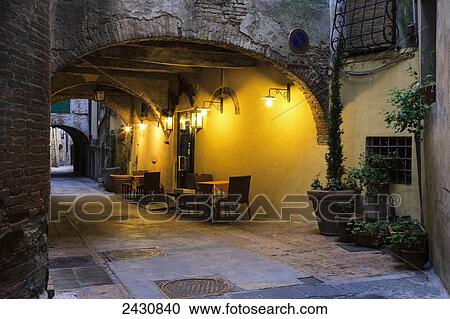 Stock Image - Seating along a wall illuminated by golden light under a covered walkway; Montepulciano, Tuscany, Italy. Fotosearch