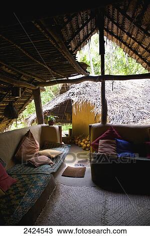 Stock Image - Seating with cushions under a slanted roof; Ulpotha, Embogama, Sri Lanka. Fotosearch
