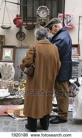 Stock Photograph - Senior Couple Shopping At El Rastro Flea Market, Madrid, Andalucia, Spain. Fotosearch