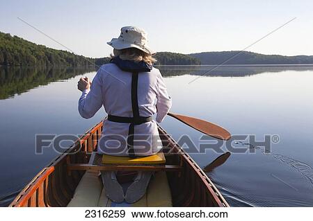 Stock Photo - Senior Woman Paddling Her Canoe On A Sunny Morning In Algonquin Park; Ontario Canada. Fotosearch