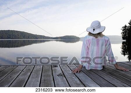 Senior Woman Sitting On Her Cottage Dock Looking Out At Lake In Algonquin Park; Ontario Canada View Large Photo Image Stock Image - Senior Woman Sitting On Her Cottage Dock Looking Out At Lake In Algonquin Park; Ontario Canada. Fotosearch
