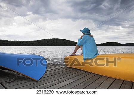 Senior Woman Sitting On Her Yellow Canoe And Looking Up At A Stormy Sky In Algonquin Park; Ontario Canada View Large Photo Image Stock Image - Senior Woman Sitting On Her Yellow Canoe And Looking Up At A Stormy Sky In Algonquin Park; Ontario Canada. Fotosearch
