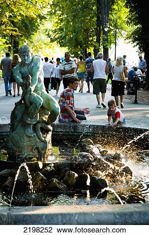 Stock Image - Serbia, Kalemegdan park; Belgrade, Family playing by fountain sparkling in sunlight. Fotosearch