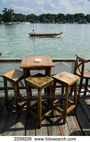 Stock Photograph - Serbia., River Danube; Belgrade, floating on river, Small boat passing by. tables and chairs. Cafe Bars. Fotosearch
