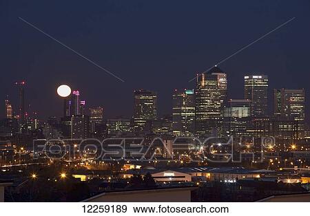 Stock Photo - Setting full moon over Canary Wharf; London, England. Fotosearch