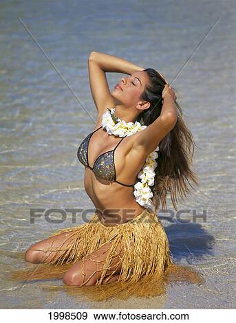 Stock Photo - Sexy Local Woman In Shoreline Water With Hula Skirt And Plumeria Lei B1412. Fotosearch