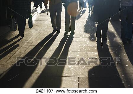 Stock Photo - Shadows of pedestrians cast on the sidewalk; London, England. Fotosearch