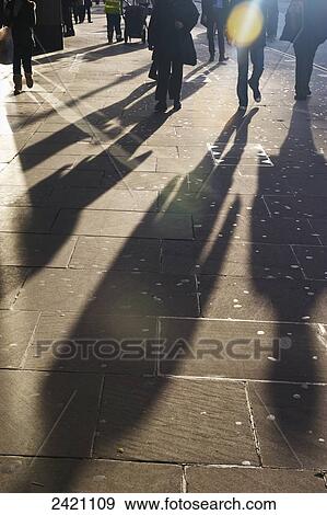 Stock Photo - Shadows of pedestrians cast on the sidewalk; London, England. Fotosearch