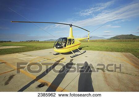 Stock Image - Shadows of people on a landing pad as a helicopter takes off; Kilauea, Hawaii, United States of America. Fotosearch