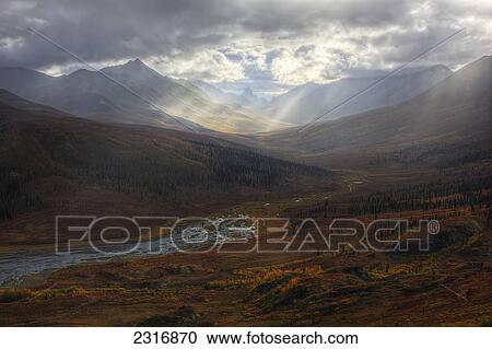 Stock Image - Shafts Of Light Burst Through The Storm Clouds In Klondike Valley Of Tombstone Territorial Park; Yukon Canada. Fotosearch