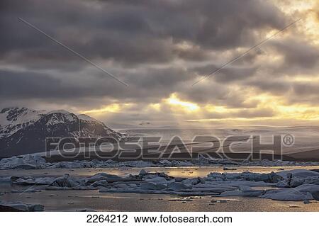 Stock Image - Shafts of sunlight shine on the ice calves floating in glacial lagoon jokulsarlon at the base of breioamerkurjokull; iceland. Fotosearch