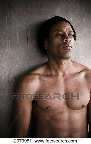 Stock Image - Shirtless Mixed Race Man Against A Concrete Wall; Vancouver, British Columbia, Canada. Fotosearch