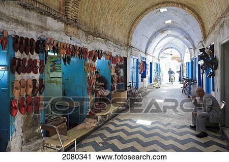 Stock Image - Shoemaker At Market In Old Town Medina Area; Kairouan, Tunisia, North Africa. Fotosearch