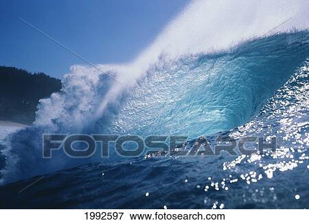 Stock Photo - Side View Of Huge Wave Crashing With Windspray, Shimmery Water Foreground.. Fotosearch