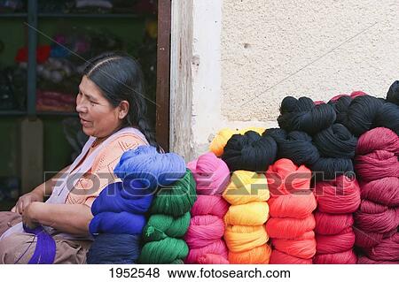 Stock Photo - Side view of woman sitting by stack of wool balls. Fotosearch