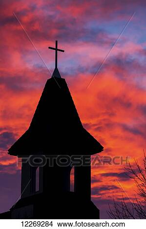 Picture - Silhouette of a church steeple with colourful clouds and blue sky in the background; Calgary, Alberta, Canada. Fotosearch