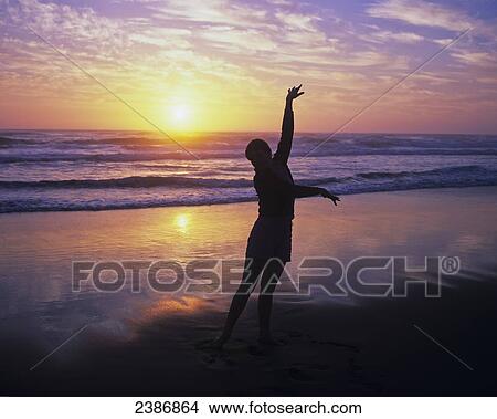 Silhouette of a girl on the beach enjoying the sunset; Winchester Bay, Oregon, United States of America View Large Photo Image Picture - Silhouette of a girl on the beach enjoying the sunset; Winchester Bay, Oregon, United States of America. Fotosearch