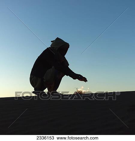 Silhouette Of A Man Heating His Hands Over A Small Fire In The Desert; Souss-Massa-Drass, Morocco View Large Photo Image Stock Image - Silhouette Of A Man Heating His Hands Over A Small Fire In The Desert; Souss-Massa-Drass, Morocco. Fotosearch