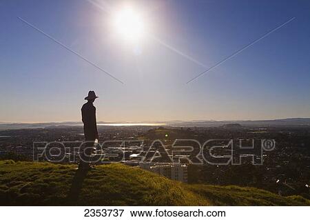 Silhouette Of A Man In A Hat Standing On Mt. Eden With A View Of Auckland; New Zealand View Large Photo Image Stock Photo - Silhouette Of A Man In A Hat Standing On Mt. Eden With A View Of Auckland; New Zealand. Fotosearch