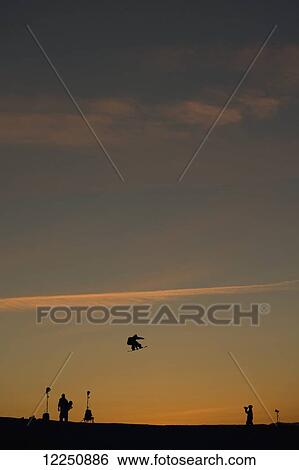 Stock Photograph - Silhouette of a snowboarder jump in mid-air at sunset; Norway. Fotosearch