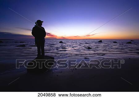 Silhouette Of A Woman Standing On Rock At Sunset, Victoria Beach, Manitoba View Large Photo Image Stock Photo - Silhouette Of A Woman Standing On Rock At Sunset, Victoria Beach, Manitoba. Fotosearch