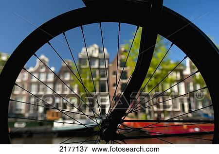 Stock Photo - Silhouette Of Bicycle Wheel In Front Of Canal & Traditional Gabled Housesamsterdam, Holland.. Fotosearch