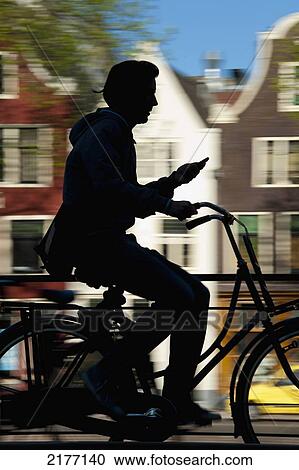 Stock Image - Silhouette Of Cyclist Going Past Canal And Gabled Housesamsterdam, Holland.. Fotosearch