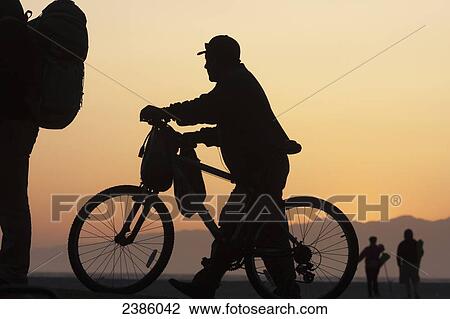 Stock Image - Silhouette of cyclists at sunrise; California, United States of America. Fotosearch