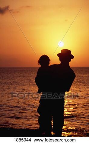 Picture - Silhouette Of Father And Child Standing In The Ocean Watching The Sunset. Fotosearch