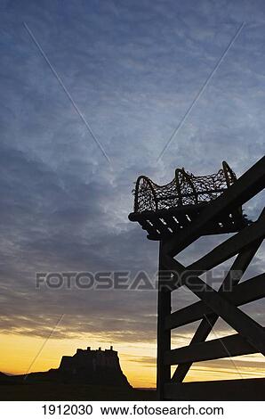Stock Image - Silhouette Of Fence And Lindesfarne Castle In Distance, Holy Island, Northumberland, Uk. Fotosearch