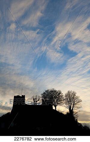 Stock Image - Silhouette of Lewes Castle with mackerel sky behind at dusk; Lewes, East Sussex, England. Fotosearch