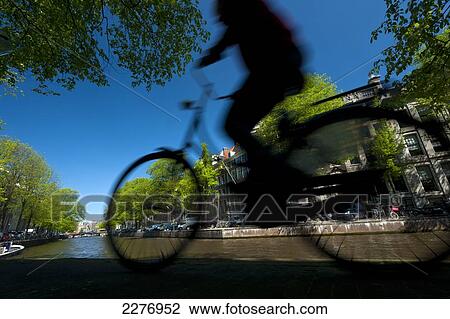 Silhouette of man cycling past canal; Amsterdam, Holland View Large Photo Image Stock Image - Silhouette of man cycling past canal; Amsterdam, Holland. Fotosearch