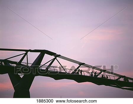 Stock Image - Silhouette Of People Crossing The Millennium Bridge At Dusk. Fotosearch