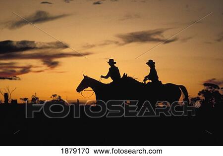 Stock Image - Silhouette Of People On Horseback At Sunset. Fotosearch