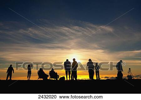 Stock Image - Silhouette of people viewing sunset at Haleakala National Park; Maui, Hawaii, United States of America. Fotosearch