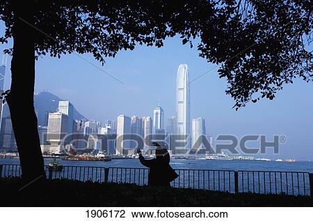 Stock Image - Silhouette Of Person Doing Tai Chi At Waterfront Park, Rear View, Hong Kong, China. Fotosearch