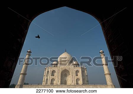 Stock Image - Silhouette of pigeon flying into doorway in front of Taj Mahal; Agra, India. Fotosearch
