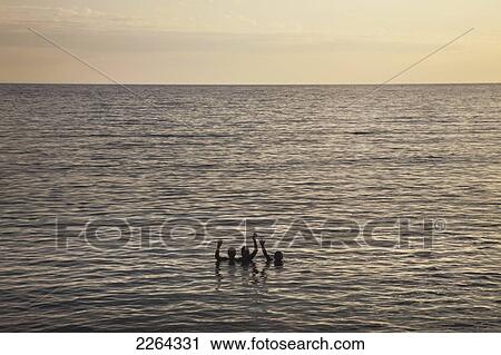 Stock Image - Silhouette of swimmers in the caribbean sea waving; chivirico cuba. Fotosearch