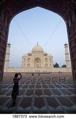 Stock Image - Silhouette Of Tourist In Arch Photographing The Taj Mahal At Dusk. Fotosearch