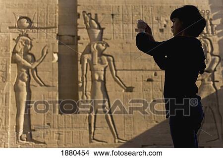 Picture - Silhouette Of Tourist Taking Photographs In Front Of Large Reliefs On Walls Of Second Pylon. Fotosearch
