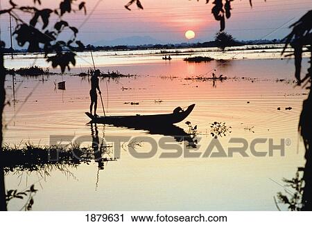 Stock Image - Silhouetted Person On A Boat On The Mekong River At Sunset. Fotosearch