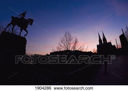 Stock Photograph - Silhouettes Of Equestrian Statue And Cologne Cathedral (Kolner Dom) At Dusk, Cologne, Germany. Fotosearch