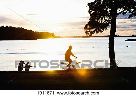 Stock Image - Silhouettes Of People At Lake Malaren Shore, Sundbyholm Manor, Sweden. Fotosearch
