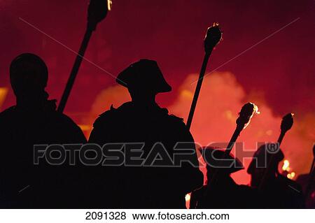 Stock Photo - Silhouettes Of Pirates With Burning Torches Lit By Red Flare Walking Through Lewes On Bonfire Night, East Sussex, Uk. Fotosearch