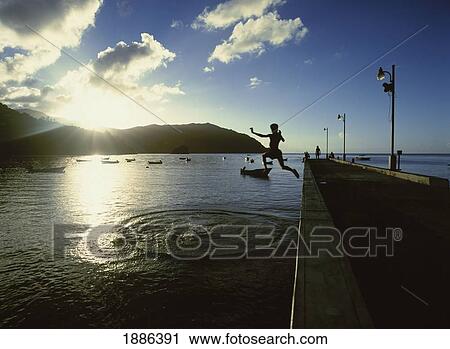 Stock Image - Sillhouette Of Boy Leaping Off The Pier. Fotosearch