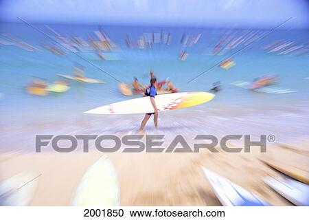 Stock Image - Single Man Carrying Board With Other Surfers Paddling Out, Blur Action. Fotosearch