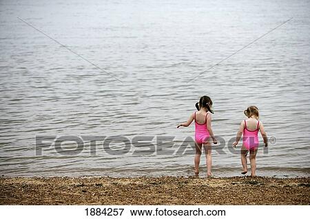 Stock Photo - Sisters In Matching Pink Bathing Suits Playing On Beach. Fotosearch